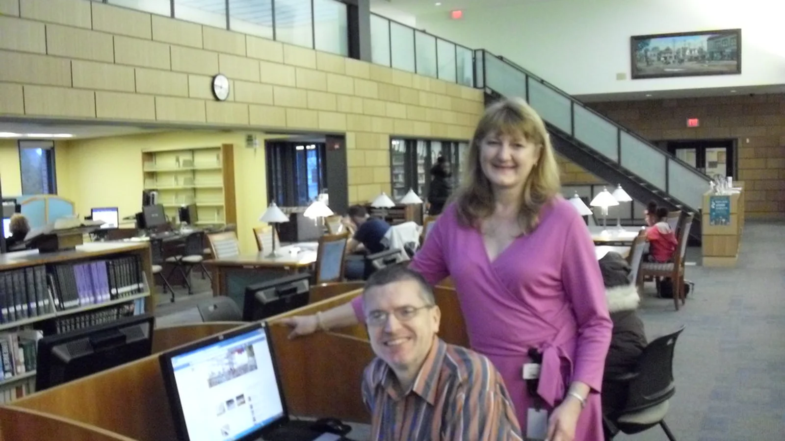 A librarian helping a patron use a computer in a library