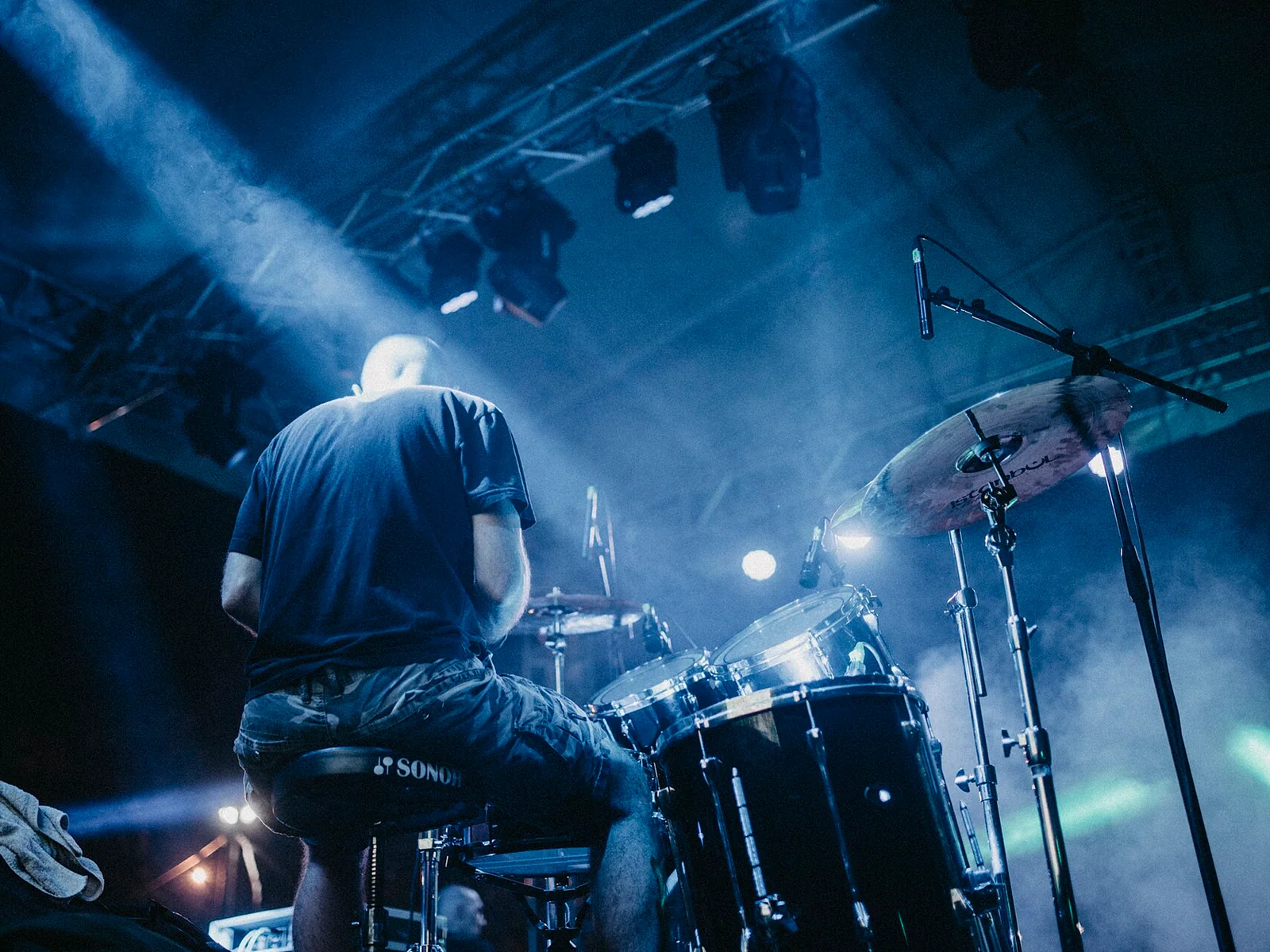 A drummer performing under stage lights during a live concert